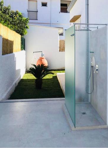 a bathroom with a glass shower in a yard at Total White Villa in Fontane Bianche