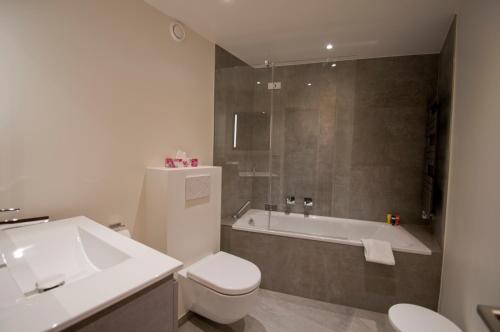 y baño con bañera, aseo y lavamanos. en La Villa Emeline - Apartment Emilie, en Zermatt