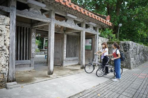 two girls standing next to a bike in front of a building at The BREAKFAST HOTEL PORTO Ishigakijima in Ishigaki Island