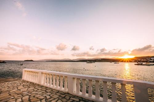 a sunset over a body of water with a white fence at Akrotiri in Analipsi