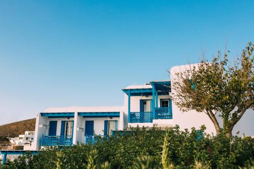 a white building with blue balconies and a tree at Akrotiri in Analipsi