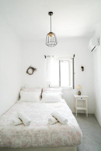 a white bedroom with a bed with two pillows on it at Plori Studios and Apartments in Aegiali