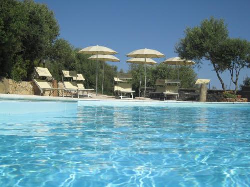 a swimming pool with chairs and umbrellas at Hotel Belvedere in Teulada