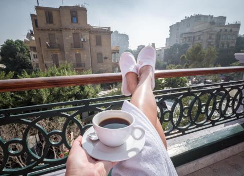 a person with their feet up on a railing with a cup of coffee at 1920s Boutique Hotel and Restaurants in Cairo