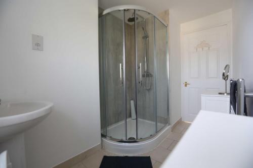 a white bathroom with a shower and a sink at 4a Dolphin Close in Lyme Regis