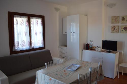 a living room with a table and a couch and a kitchen at Trilocale Vignola Mare in Aglientu