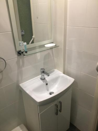 a white bathroom with a sink and a mirror at Milton Lodge in Weston-super-Mare