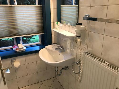 a bathroom with a white sink and a window at Friesenhof Nieblum - Hotel Garni in Nieblum