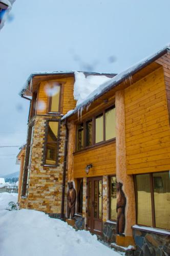 a log cabin with two bear statues outside of it at Synevyrskyj Chardash in Synevyr