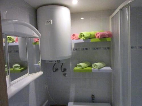 łazienka z zielonymi i różowymi ręcznikami na półkach w obiekcie apartman Lucija w mieście Punat
