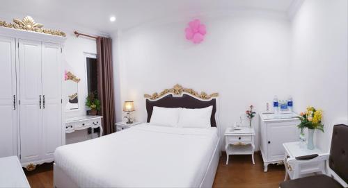 ダラットにあるCarita Hotelの白いベッドルーム(大型ベッド1台、デスク付)