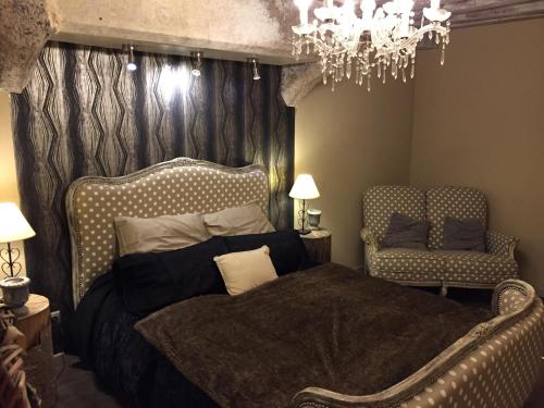 ein Schlafzimmer mit einem Bett, einem Stuhl und einem Kronleuchter in der Unterkunft Le Gite des Tourelles in Bèze