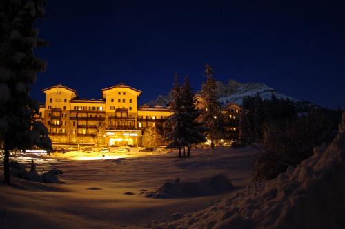a large building in the snow at night at Residence Grand Hotel Carezza in Nova Levante