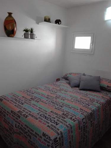 a white bedroom with a bed with a colorful blanket at Hotel Centrale in Siracusa