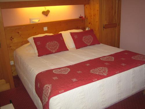 a bedroom with a bed with red pillows at Chalet Hotel Régina in Les Gets