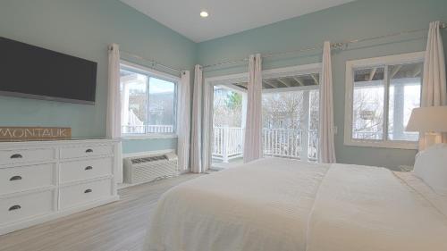 a bedroom with a bed and a tv and windows at Sea Crest in Amagansett