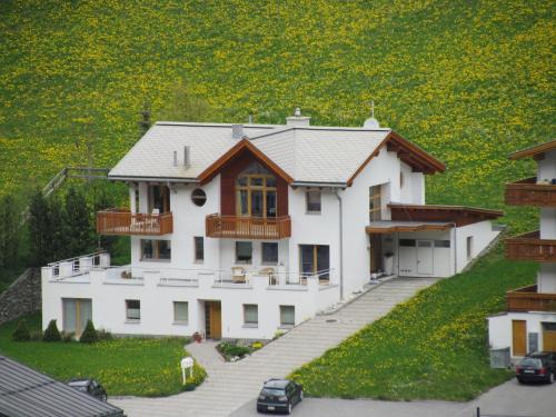 a large white house in front of a field of flowers at Apartment MEZPRA in Samnaun