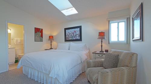 a bedroom with a white bed and a chair at Sea Crest in Amagansett