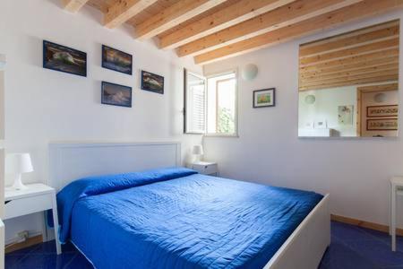 a white bedroom with a blue bed and a window at Le Case di VirGin 1 in Castellammare del Golfo