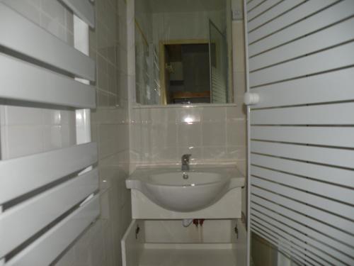 a white bathroom with a sink and a mirror at Au Coeur De La Station in Les Deux Alpes