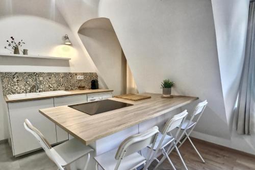 uma cozinha com uma mesa de madeira e cadeiras brancas em Les appartements d'Edmond Saint Suffren em Marselha