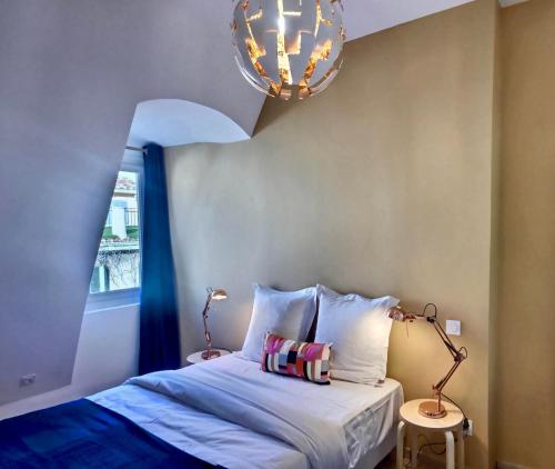 um quarto com uma cama com uma janela e um lustre em Les appartements d'Edmond Saint Suffren em Marselha
