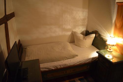 a small bed in a small room with a lamp at zum Frongut in Burgstaedt