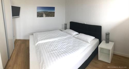 a bedroom with a white bed with a black headboard at Meermomente in Helgoland
