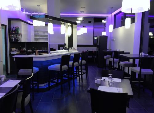ein Restaurant mit lila Beleuchtung sowie Tischen und Stühlen in der Unterkunft Motel Chute des Pères in Dolbeau