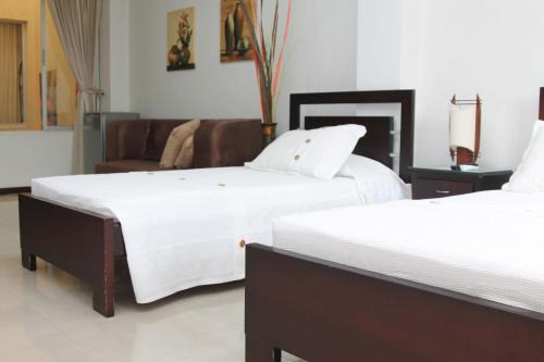 a bedroom with two beds and a couch at Pampalinda Hotel in Cali