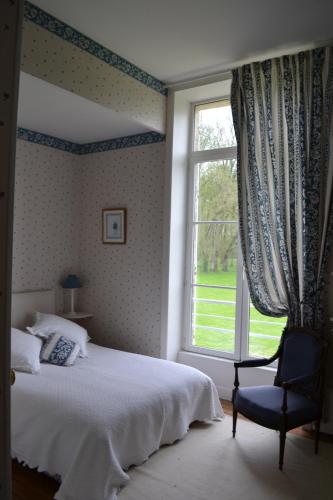 um quarto com uma cama, uma cadeira e uma janela em Château de SURY em Saint-Jean-aux-Amognes