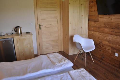 a bedroom with a bed and a white chair at Maniówka - pokoje i domki w Bieszczadach in Maniów