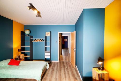 1 dormitorio con paredes azules y amarillas y 1 cama en Maison des Orfèvres, en Arbois