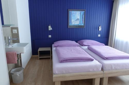 ein Schlafzimmer mit 2 Betten und einer blauen Wand in der Unterkunft Mischi in Saas-Fee
