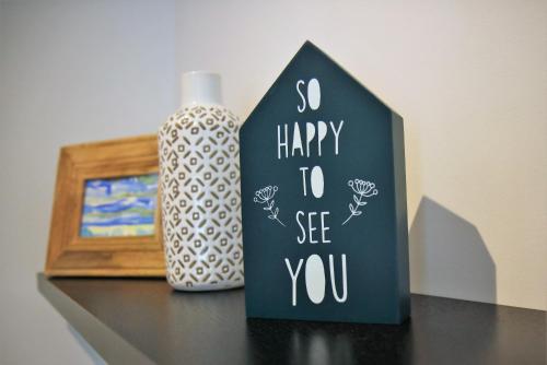 a blackhappy to see you sign next to a vase at Pine Tree Apartments - Praia da Coelha - Albufeira in Albufeira