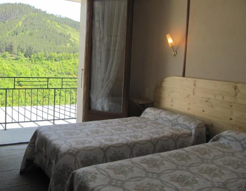 a hotel room with two beds and a balcony at Hôtel Des Rochers in Marvejols