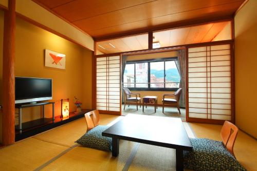 a living room with a table and a tv at Seaside Hotel Mimatsu Ooetei in Beppu