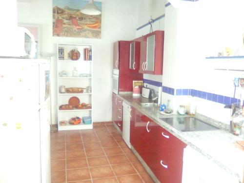 uma cozinha com armários vermelhos e um frigorífico branco em El Mirador de la Desembocadura em Ayamonte