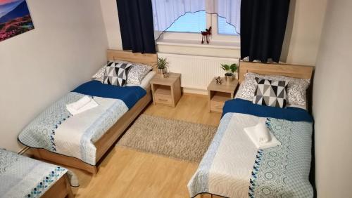 a small room with two beds and a window at Apartman May Tatranska Lomnica in Tatranská Lomnica