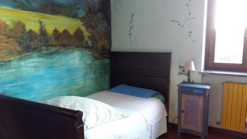 1 cama en un dormitorio con una pintura en la pared en Il Nido del Pettirosso, en Borgomanero