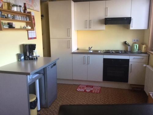 a kitchen with white cabinets and a stove top oven at Gîte Les Montagnes in Bolandoz