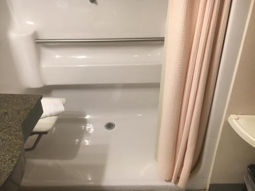 a bathroom with a bath tub and a shower curtain at Hotel Grand Victorian in Branson