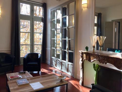 a living room with a table and windows at Les Suites du Cours & Spa in Aix-en-Provence