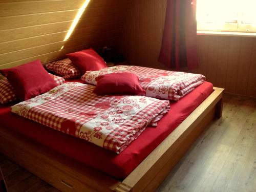 łóżko z czerwoną i białą kołdrą w obiekcie Heidekäfer Ferienhaus Eichhörnchen w mieście Kirchlinteln