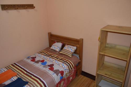 a small bedroom with a bed and a shelf at Hostal Kuyllur Ñan in Zumbahua