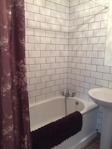 La salle de bains est pourvue d'une baignoire et d'un lavabo. dans l'établissement Mews Cottage, à Seaford