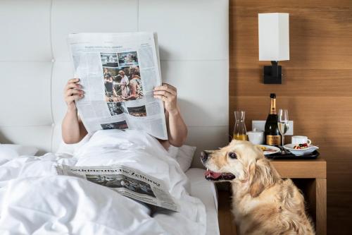 a man laying in bed reading a newspaper with a dog at Vinschgerhof in Silandro
