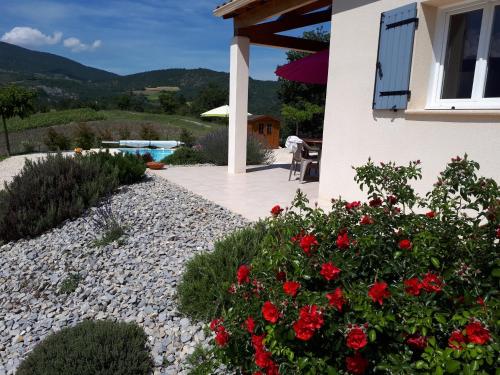 a garden with red flowers and a house at LES HAUTS DE JALLIA in Sainte-Jalle
