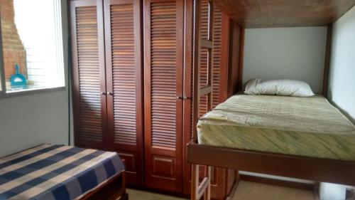 um quarto com uma cama e um closet com portas de madeira em Cobertura Enseada Guarujá no Guarujá