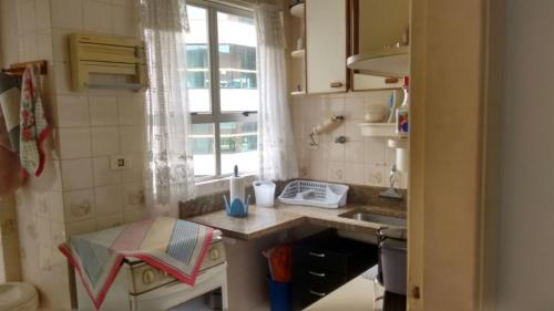 uma pequena cozinha com um lavatório e uma janela em Cobertura Enseada Guarujá no Guarujá